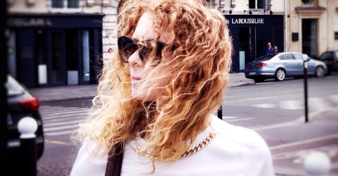 Woman with curly red hair wearing sunglasses on a city street