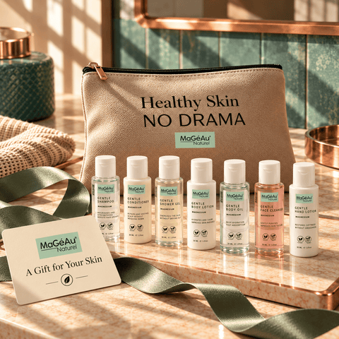 A MaGeAu Nature skincare gift set arranged on a marble surface, featuring a beige zip pouch with the text 'Healthy Skin NO DRAMA' and eight small white bottles of cleansers, toners, and moisturizers. A gift card reading 'A Gift for Your Skin' is placed in front, with a green ribbon draped across the scene.