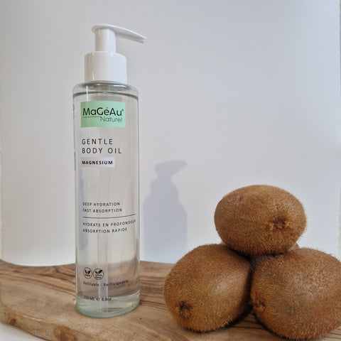 Mageau Magnesium Gentle Body Oil bottle with kiwis on a wooden surface
